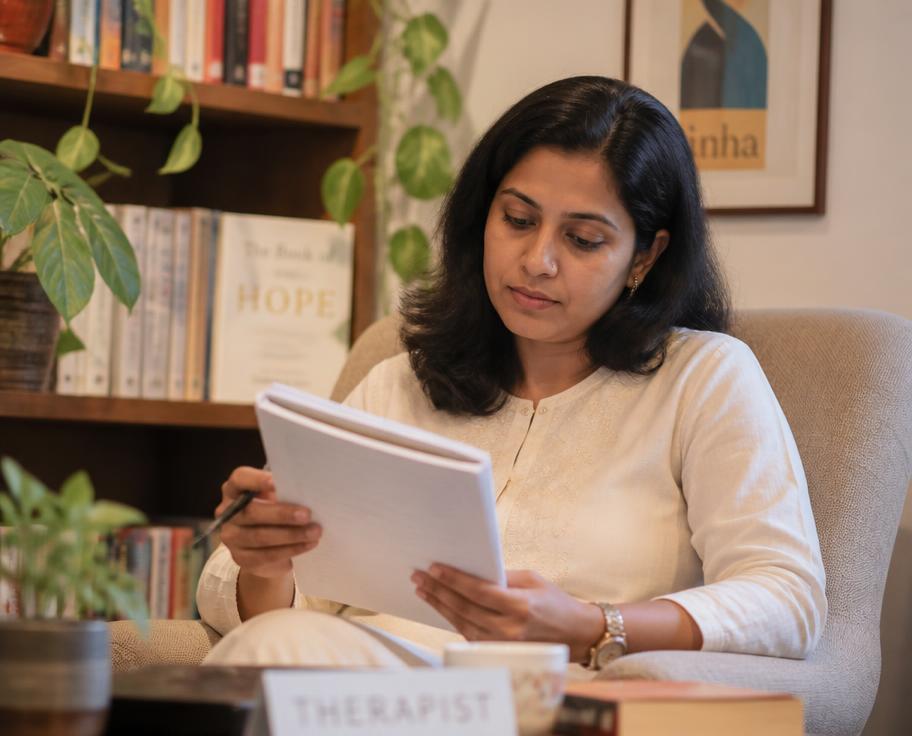 A therapist reading case notes in a warm, book-lined room